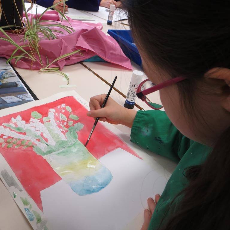 a vase with flowers being painted by a student