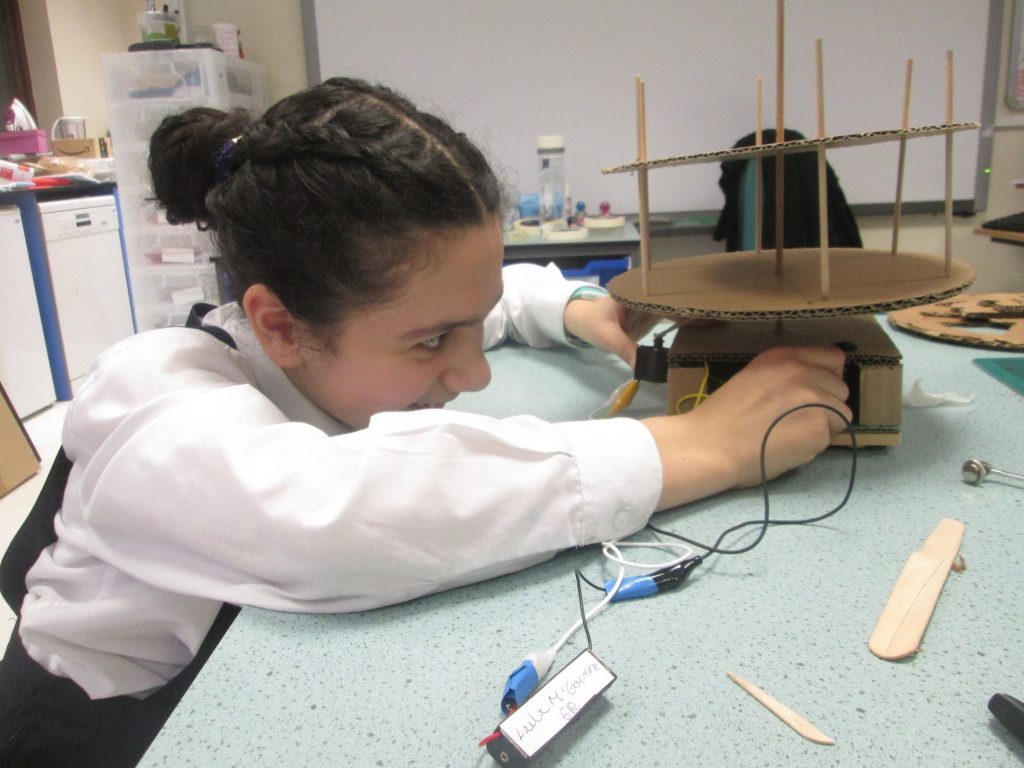 girl assembling a structure using pieces of wood