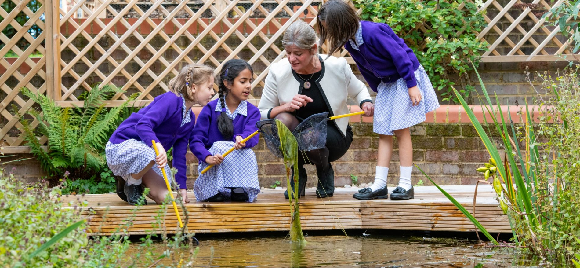 Head teacher looking at pond with school girls