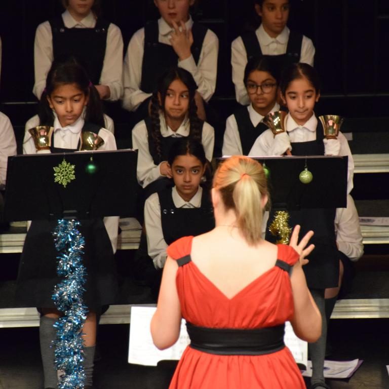 girls singing, with the conductor directing