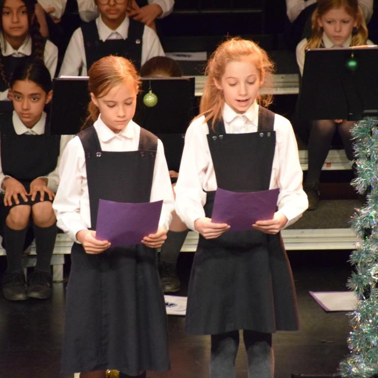 2 students singing, reading from the song sheet